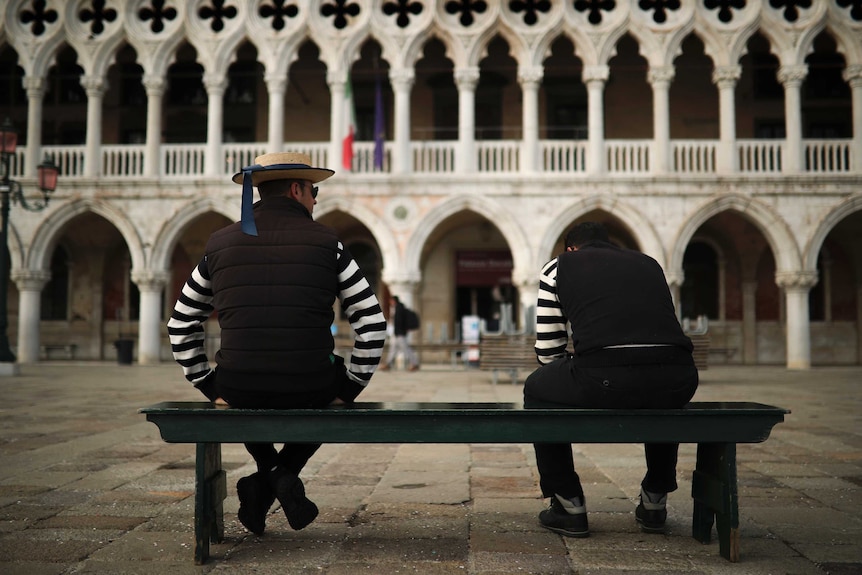 Stripey-shirted gondoliers chat as they wait for customers near St. Mark's square in Venice.