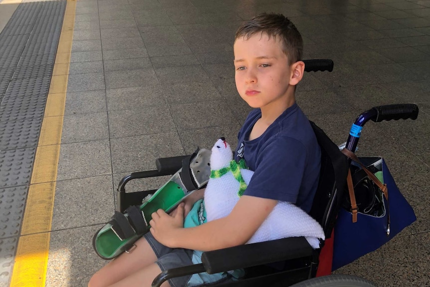 10-year-old Lewis Railton sitting in his wheelchair at the bus stop.