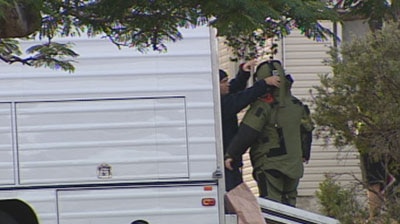 Bomb squad detectives search the home of the accused.