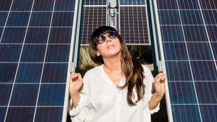 FEAT. founder Heidi Lenffer standing among a solar panel array