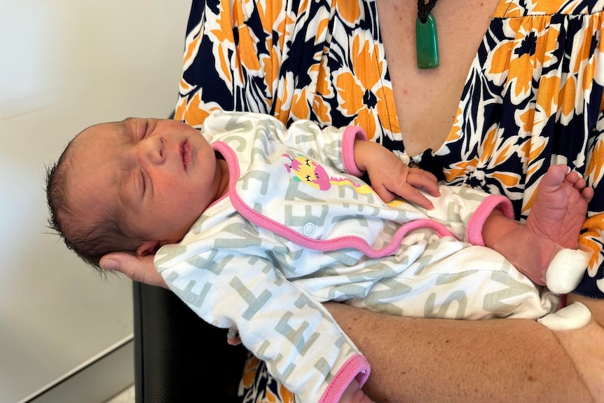 Close up of baby sleeping in mother's arms. 