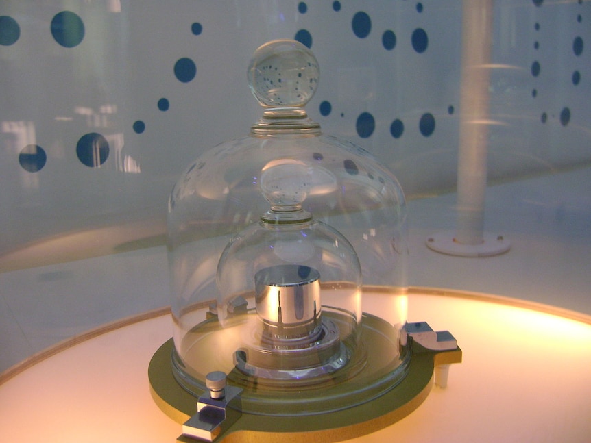 A metal cylinder inside two glass bell jars.
