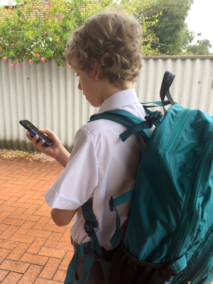 A school boy texts on a mobile phone.