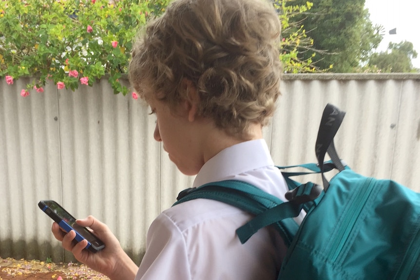 A school boy texts on a mobile phone.