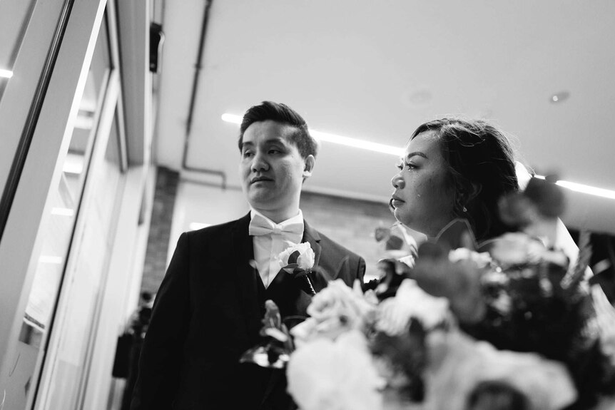 A groom and bride seeing his grandparents through a glass window on his wedding day