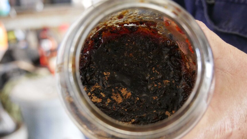 Close up of IMO 2. A brown paste with a jam like texture in an old instant coffee jar.