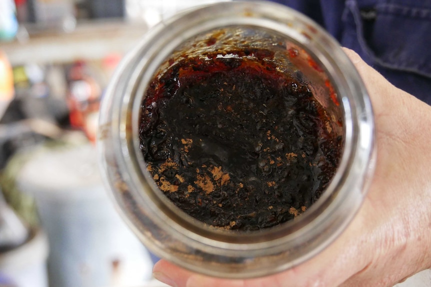 A brown paste with a jam like texture in an old instant coffee jar. Mix of mouldy rice and brown sugar.
