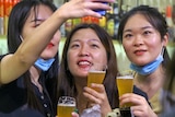 Three girls taking a selfie while holding glasses of beer