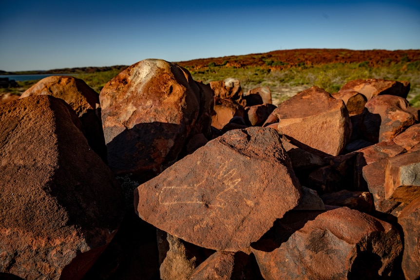 A rock carving in Murujuga, Western Australia, shows a hand print, on red rock. 