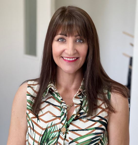 A woman with long brown hair and a green, brown, and white sleeveless shirt