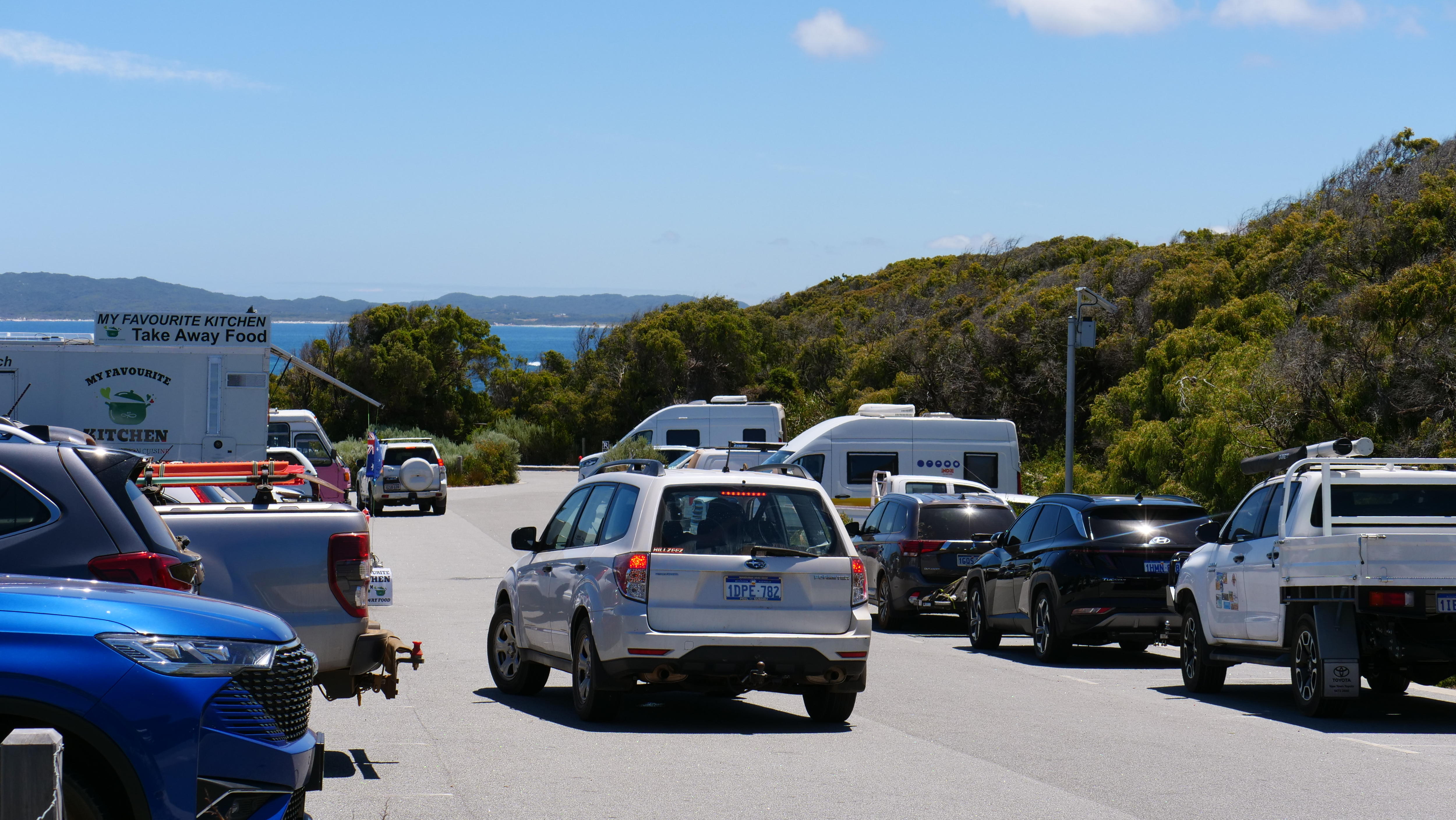 O estacionamento Greens Pool com muitos carros e o oceano ao fundo.