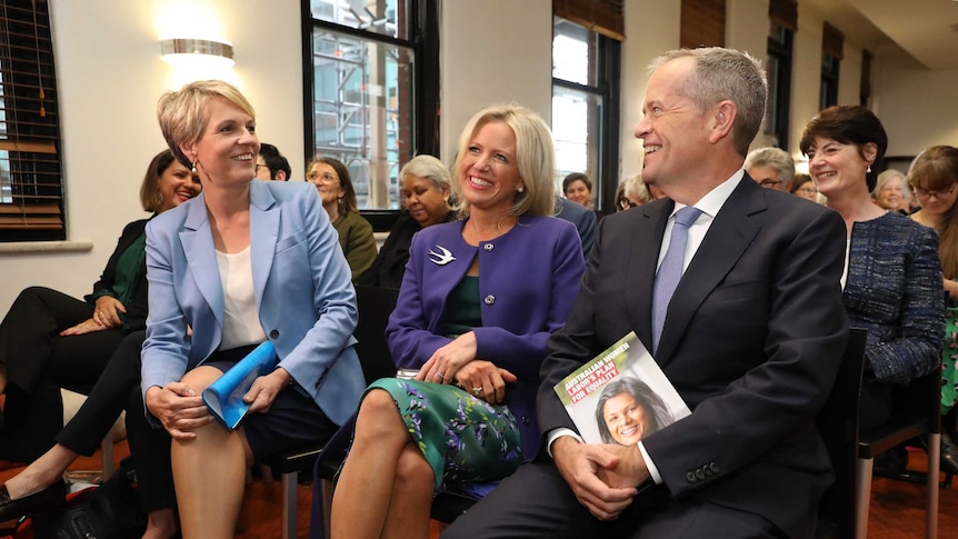 Mr Shorten and Ms Plibersek are looking at each other smiling while Mrs Shorten, sitting in the middle, smiles as she looks ahea