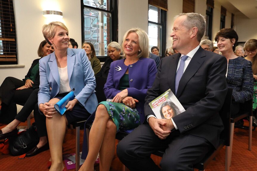 Mr Shorten and Ms Plibersek are looking at each other smiling while Mrs Shorten, sitting in the middle, smiles as she looks ahea