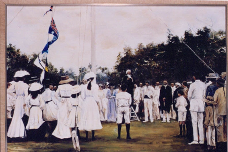 A photo painted in the early 1900s shows a group of men and women standing around a flag pole.