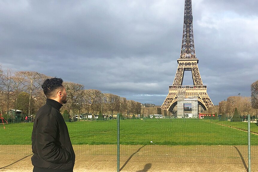 Adam stands by looking at the Eiffel Tower in Paris.
