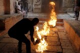 A Palestinian protester kicks a burning tyre