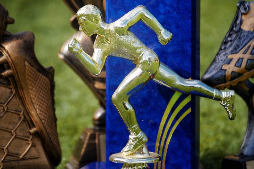 A close up of an athletics trophy with a blue background and gold running man.