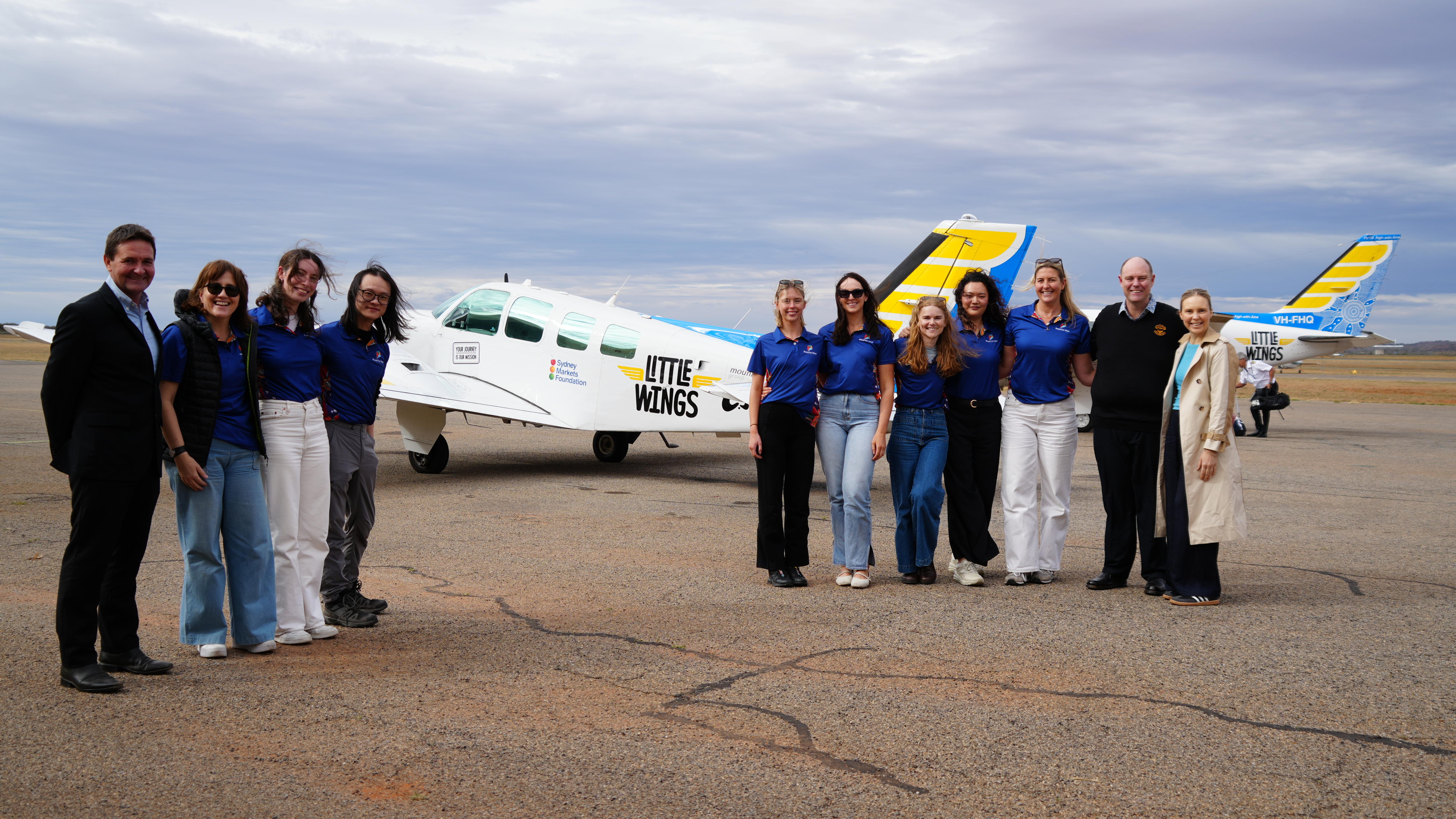 Photo of people posing with a small aircraft