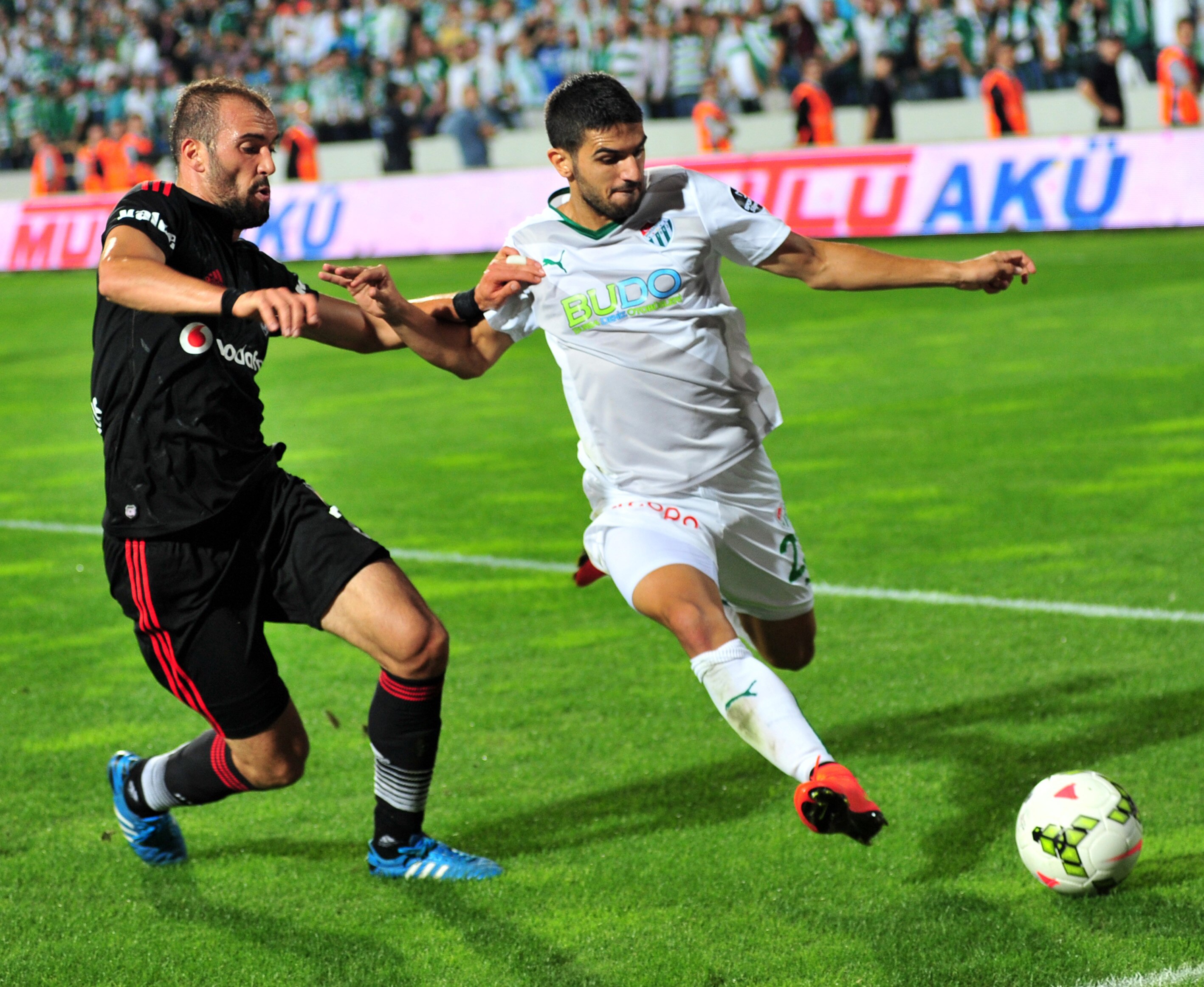 Two male soccer players, one wearing black and the other wearing white, during a match
