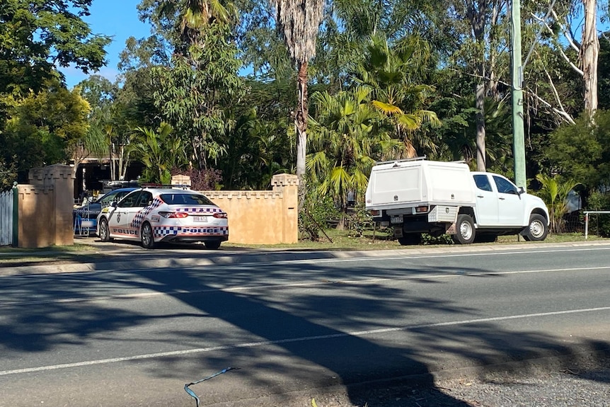 Two police cars parked out front of a house with police tape.