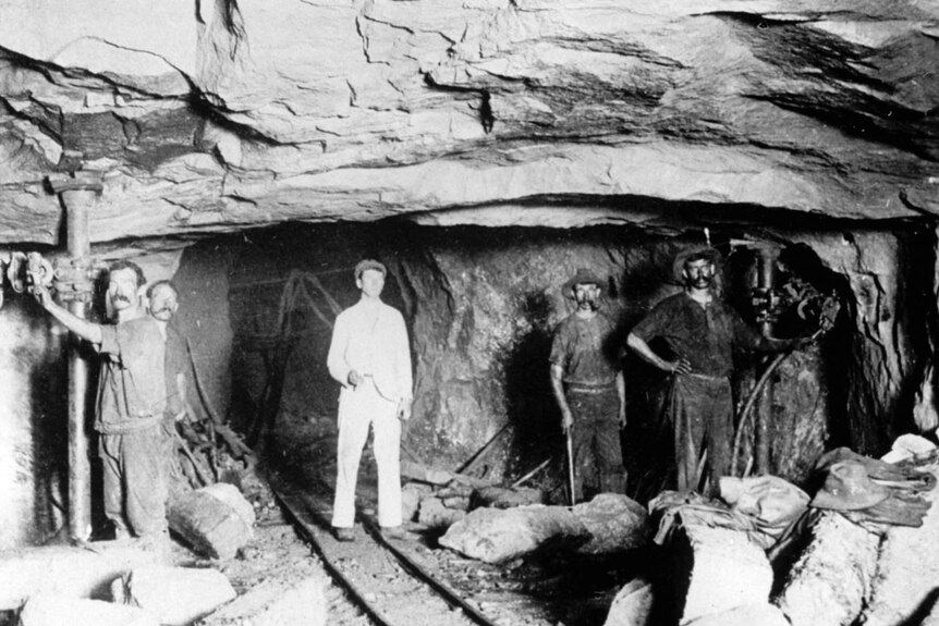 A black and white archive photo of five miners, all men, underground
