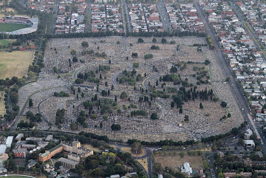 Aerial view of an expansive cemetery surrounded by roads and housing. 