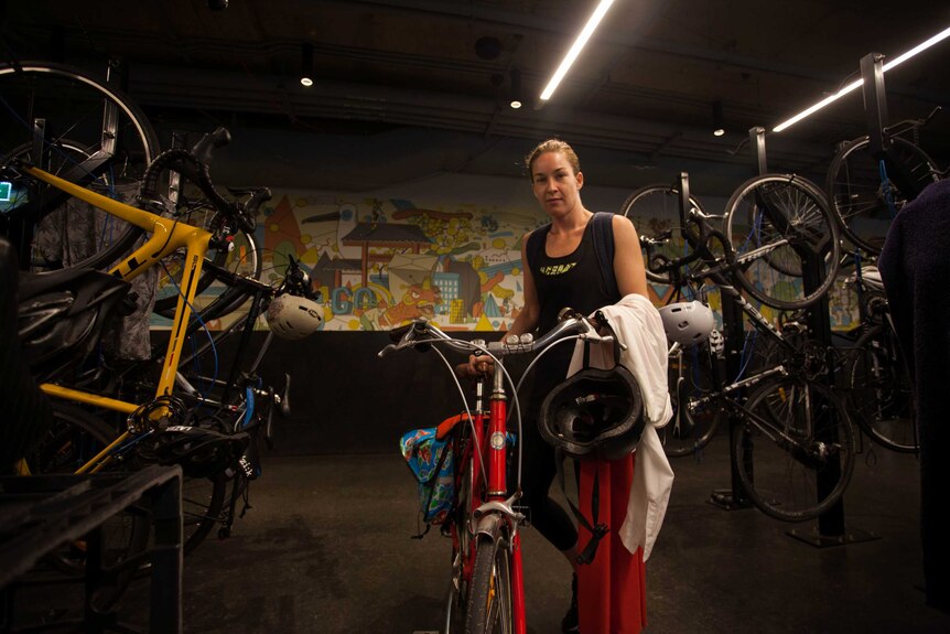 City of Sydney council deputy mayor Jess Miller pushes a bicycle into an indoor bicycle lock up area