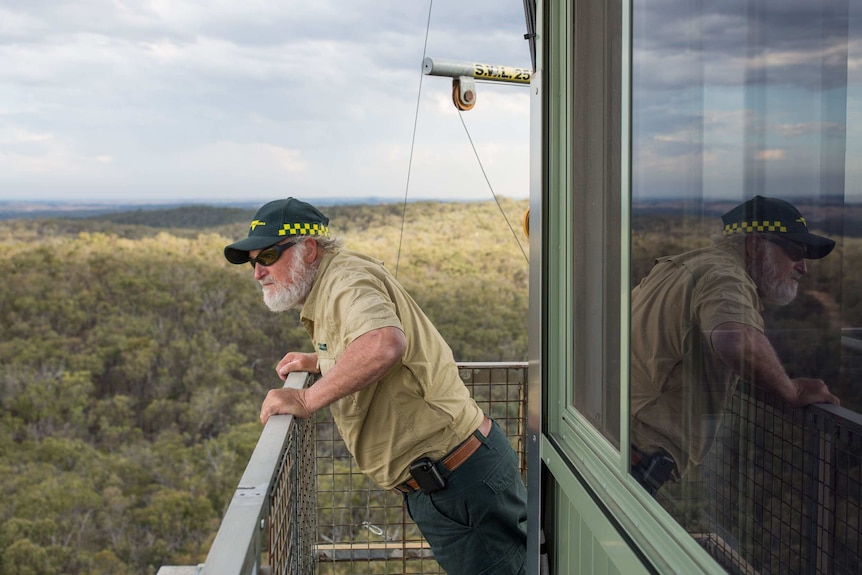 Fire tower observer Paul Leishman does pushups off the rail of his tower, the expanse of the Fryers Ridge State Forest behind.