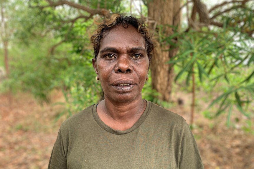an aboriginal woman wearing a green shirt in the bush