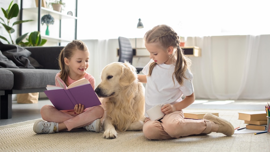 two girls with their pet dog sitting on the floor