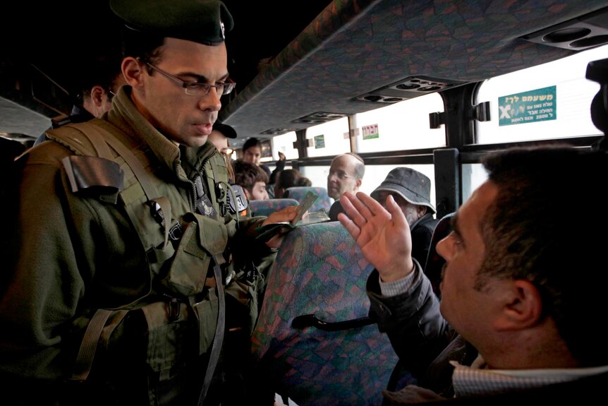 An Israeli soldier checks the identity card of a Freedom Rider on a bus at a checkpoint.