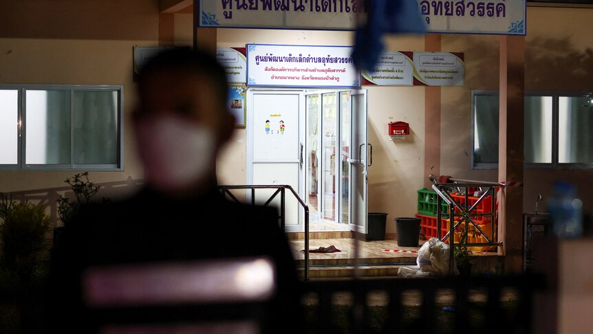 A police officer walks past the entrance of a day care centre while wearing a mask.