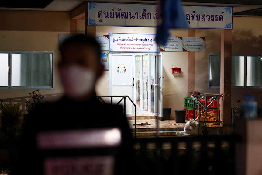 A police officer walks past the entrance of a day care centre while wearing a mask.