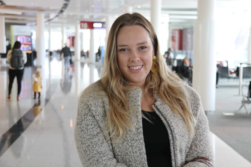 A blonde girl smiles at the airport