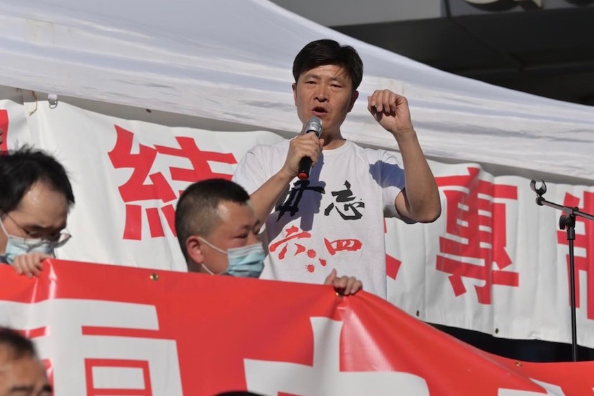 A man raises his fist alongside red and white banners.