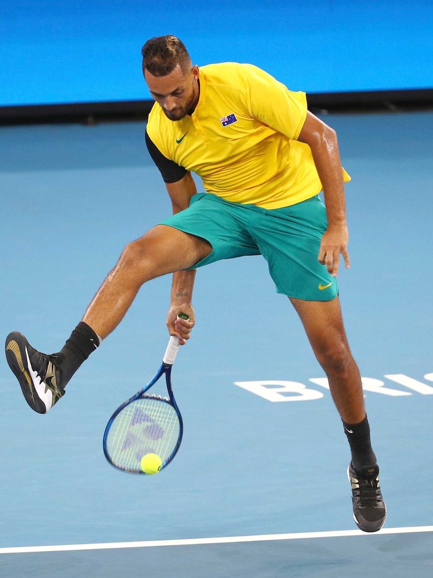 A tennis player plays a shot through his legs mid-air.