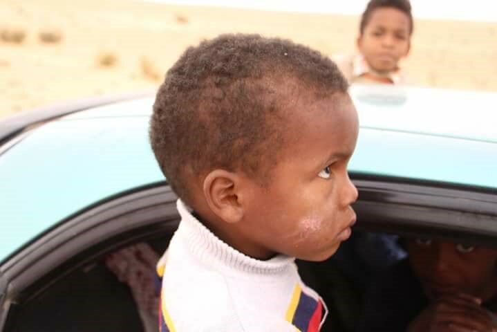 Children wait in cars in the desert to enter Tawergha