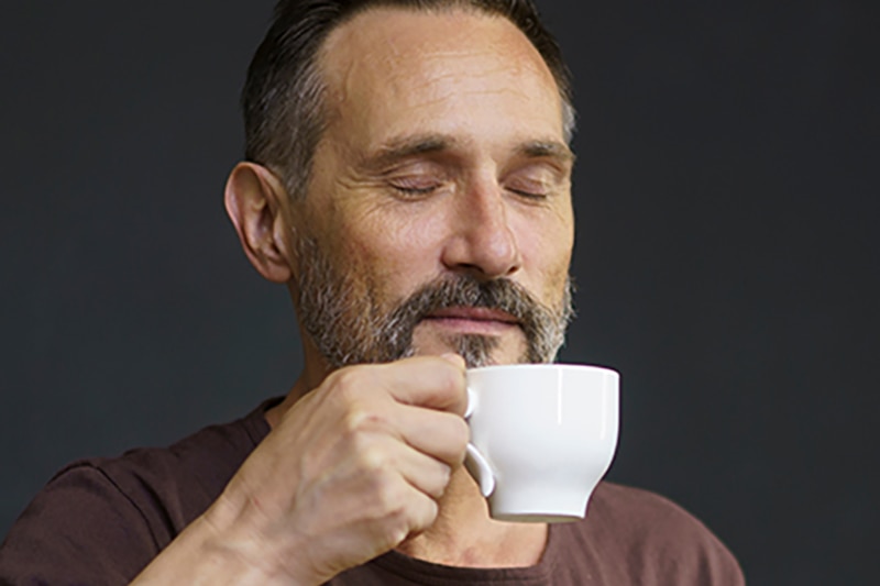 Man with eyes closed drinking coffee