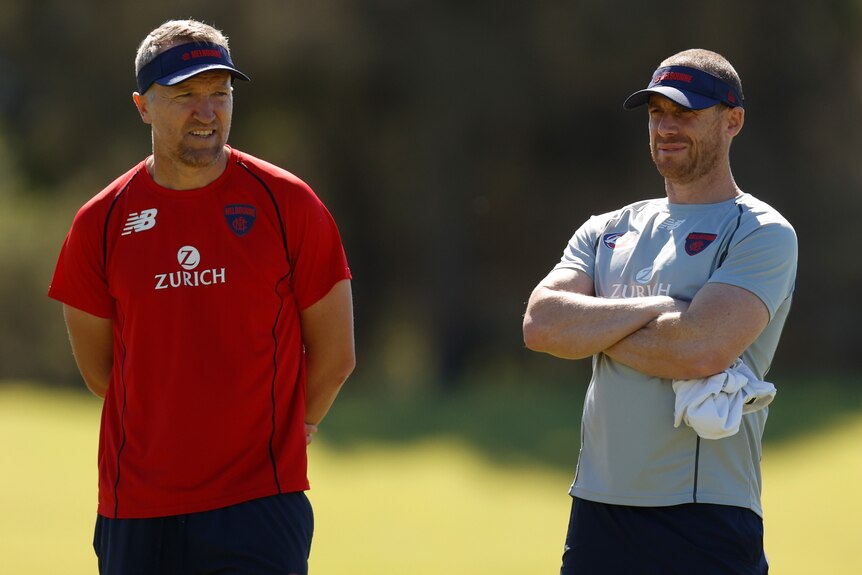 Two AFL coaches standing side by side 