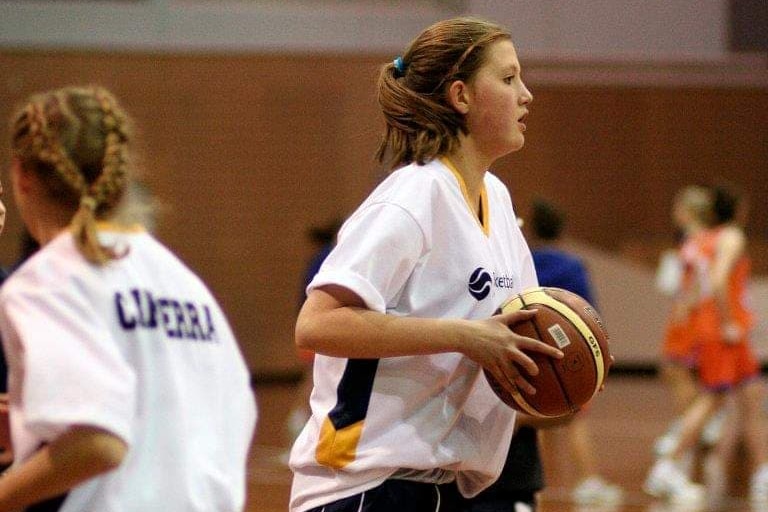 A young teenager plays basketball.