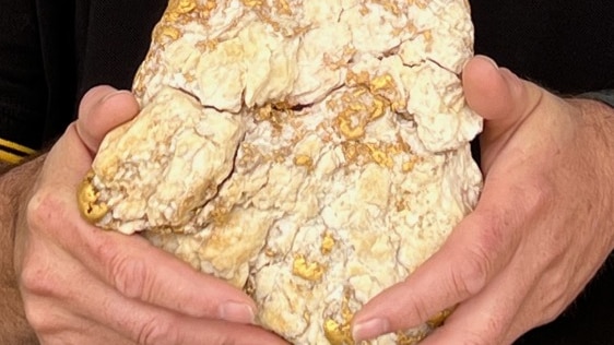 a gold nugget sits in a man's hands