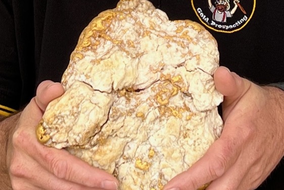 a gold nugget sits in a man's hands
