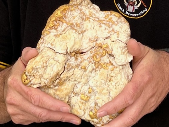 a gold nugget sits in a man's hands