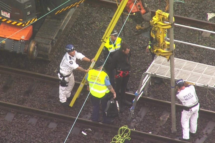 Police arresting a man at the foot of a ladder