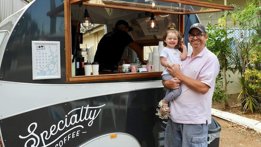 Man holds little girl at coffee cart window