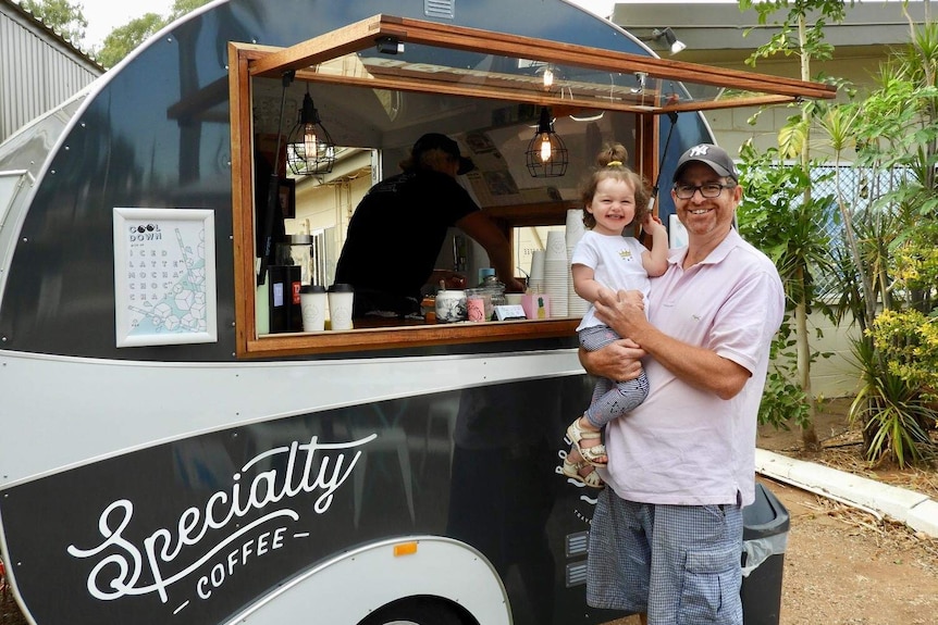 Man holds little girl at coffee cart window