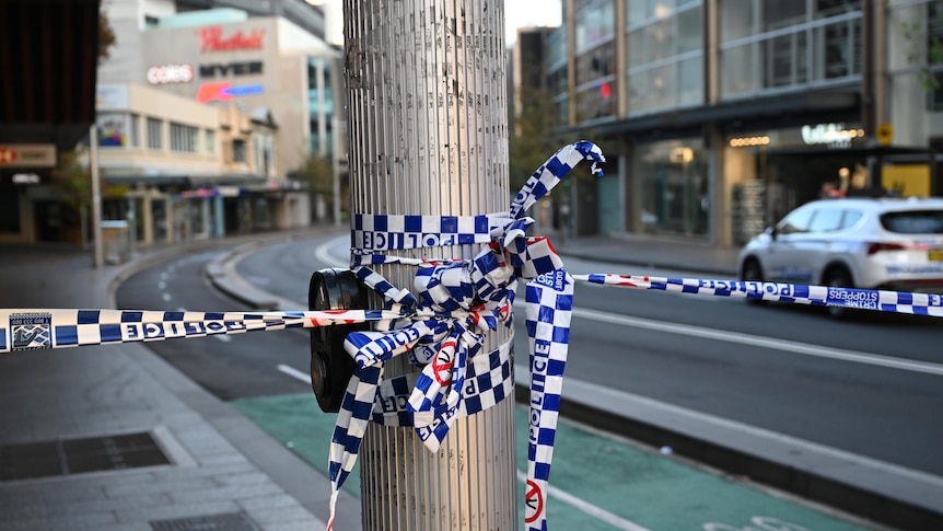 Police tape wrapped around a metal pole.