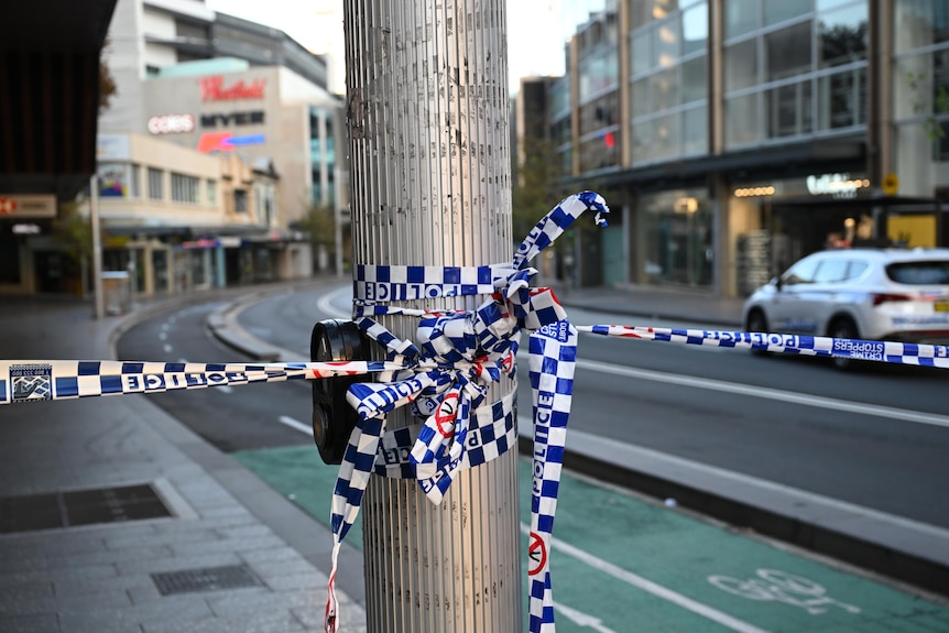 Police tape wrapped around a metal pole.
