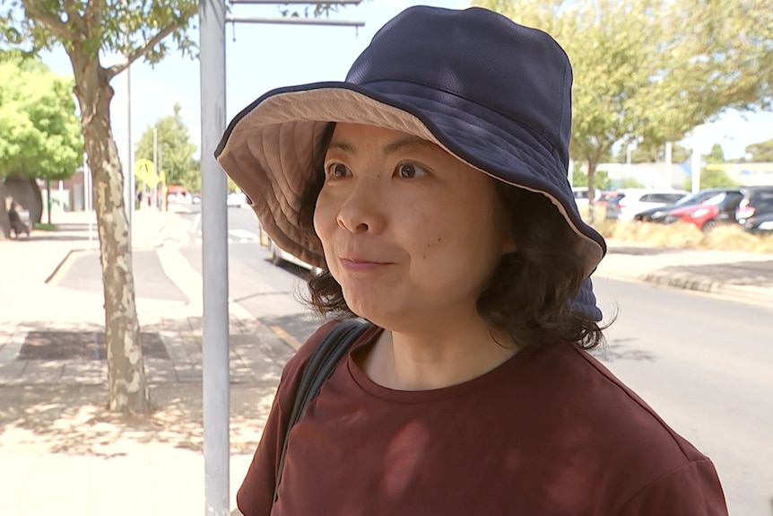 A woman with short brown hair wearing a bucket hat. 