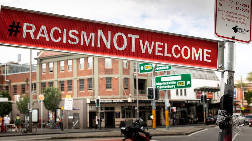 A road sign that says #RacismNOTWelcome is seen on a street corner in Sydney